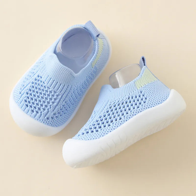 Pair of light blue baby shoes on a beige background