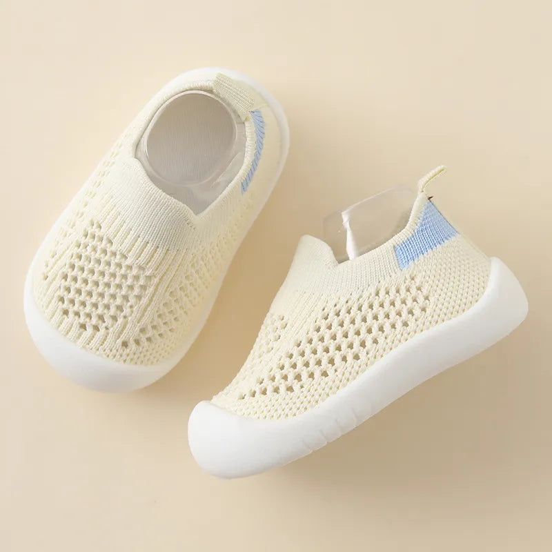 Pair of yellow baby shoes with blue accents on a beige background