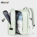 Light green backpack with open front compartment showing blue jeans and white shirts on a white background, featuring the WELLVO brand.