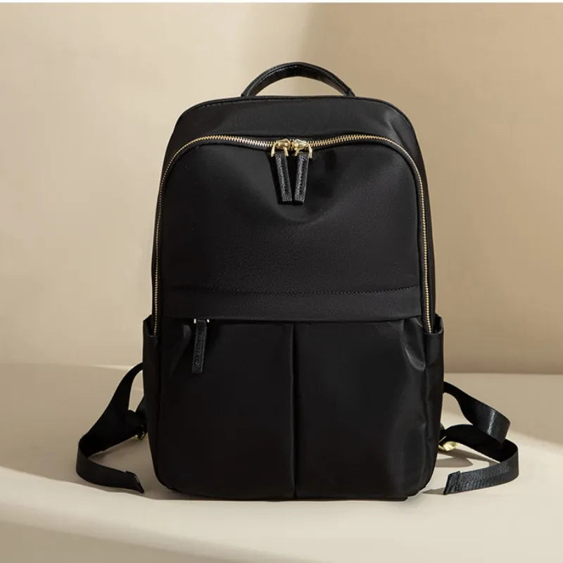 Black backpack with gold zipper on a beige background