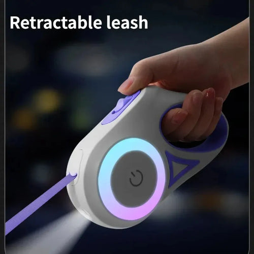 Illuminated purple retractable leash device with hand holding it against a dark background