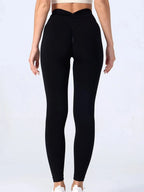 Back view of person wearing black high waist v-back leggings against a neutral background