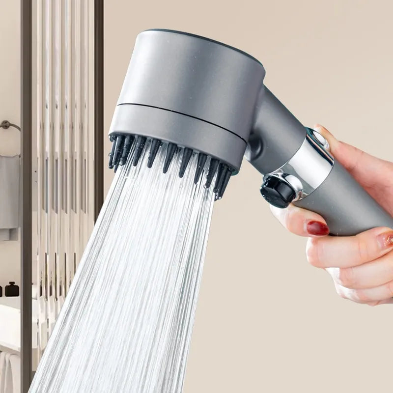 Handheld massaging shower head with water flowing, held by a hand against a neutral background