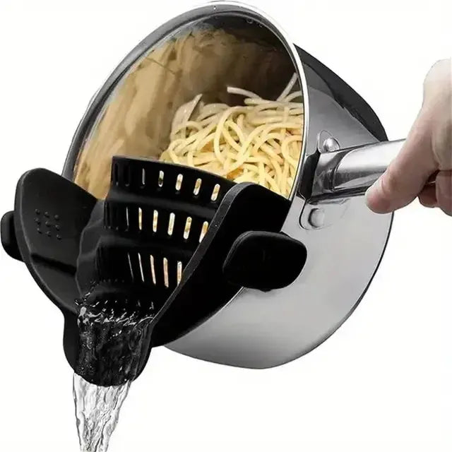 Pasta being drained with a black silicone strainer from a steel pot on white background
